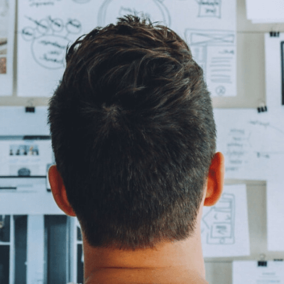 The back of a person’s head with a whiteboard in the background.