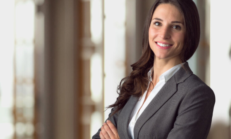 Female GDLP student wearing a suit with arms folded, in a office building