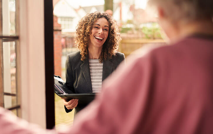 Woman laughs at person, blurry in foreground. She is holding an open compendium.