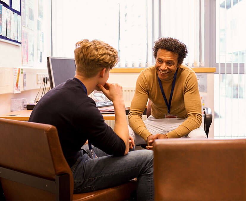 Smiling man sitting at a desk and chairs, meeting with a young client