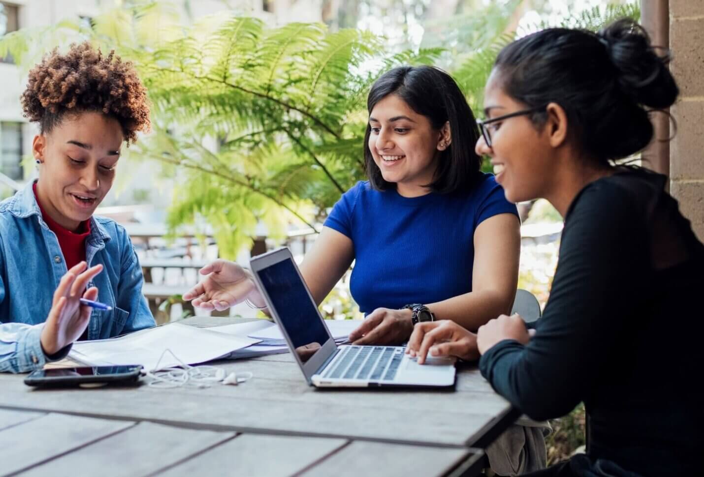 Three people happily discuss something at a table.