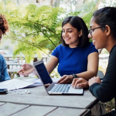 Three people happily discuss something at a table.