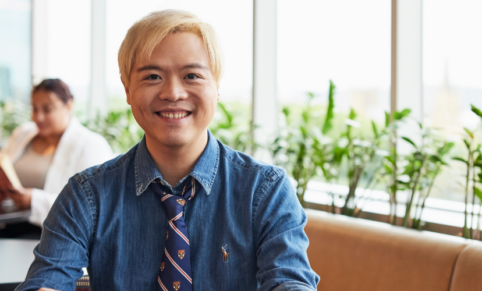 young man with blonde dyed hair in tie smiles at camera