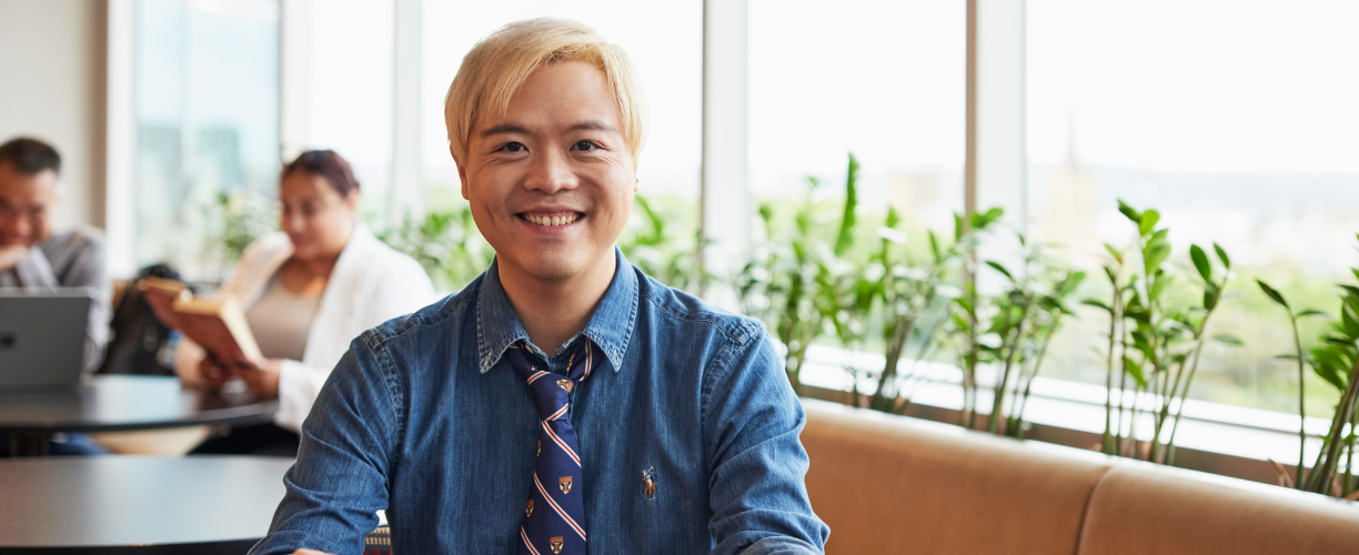 young man with blonde dyed hair in tie smiles at camera