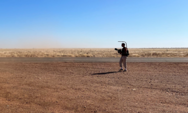 image of desert landscape with a man holding a filming rig in distance right