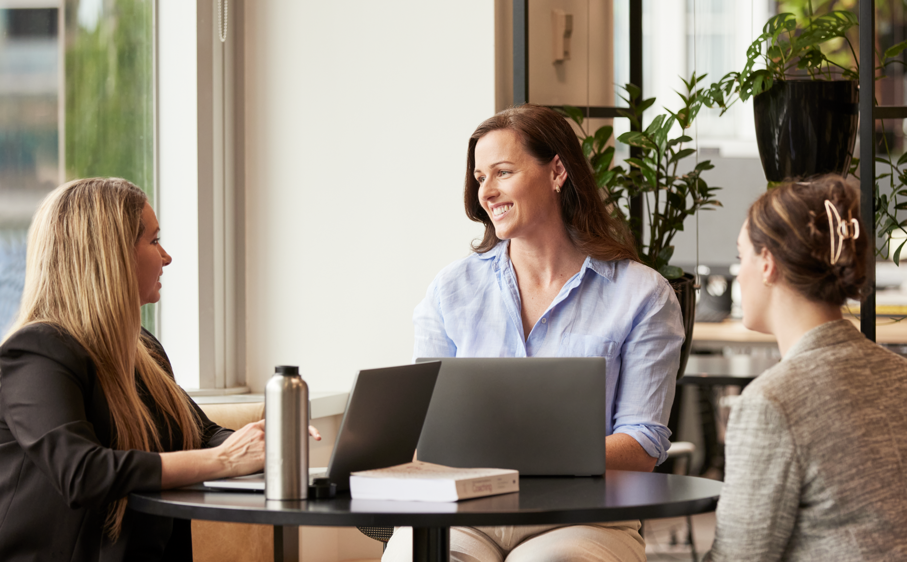 Woman speaking to two other women in corporate setting