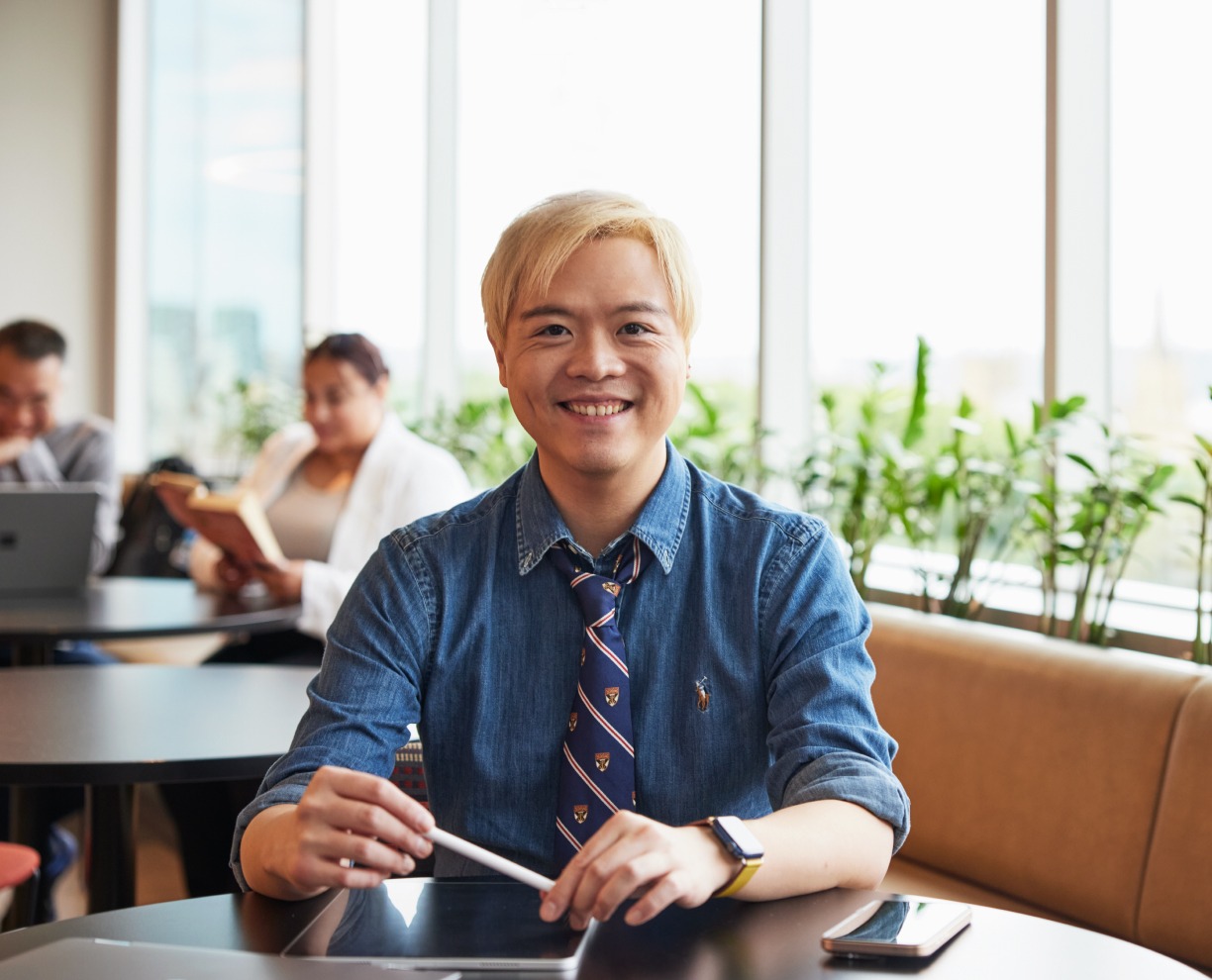 Photo of Psychology student and lecturer Tidus, sitting at ACAP Sydney campus and smiling to camera